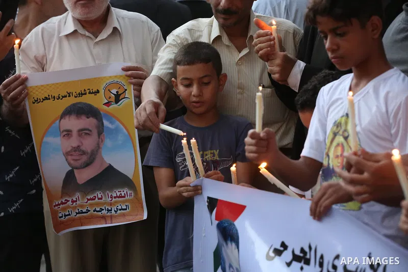 Palestinians hold banners and light candles during a protest in solidarity with Palestinian prisoner in Israeli jails suffering from cancer Nasser Abu Hamid, in front of Red cross office, in Gaza city on September 13, 20...