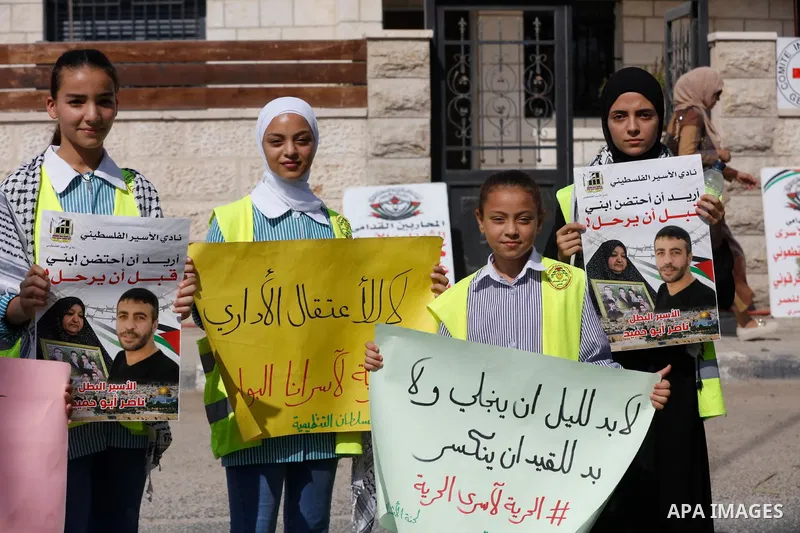 Palestinians hold banners during a protest in solidarity with Palestinian prisoner in Israeli jails suffering from cancer Nasser Abu Hamid, in front of Red cross office, in the West Bank city of Jericho on September 14,...