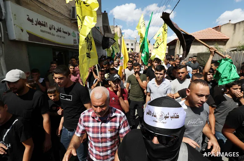 Palestinian fighters and civilians march in the village of Kafr Dan, to show solidarity with the families of 2 Palestinians killed in overnight clashes with Israeli security forces near a checkpoint inorth of the West Ba...