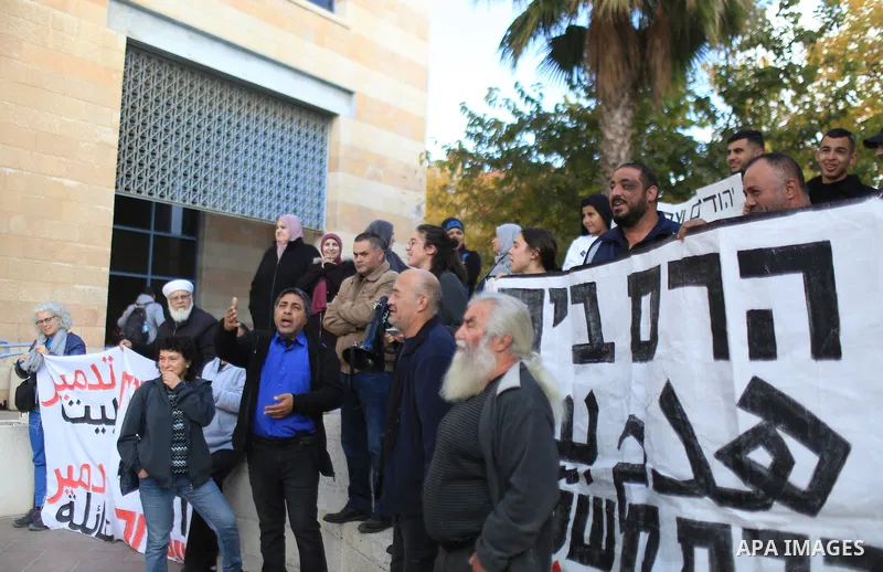 Palestinians take part hold banners dunring a protest against the decision of the Israeli authorities to demolish a building in the Wadi Qaddum neighborhood of Silwan, Jerusalem on December 6, 2022. Photo by Saeed Qaq\ a...
