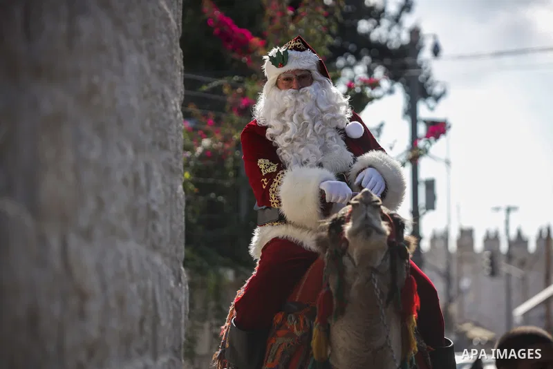 Palestinian Issa Kassissieh, dressed as Santa Claus, poses for a picture as he rides a camel at the Mount of Olives in Jerusalem, a few weeks before the upcoming holiday of Christmas on December 6, 2022. In Jerusalem's O...