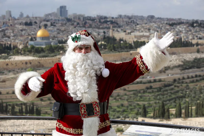 Palestinian Issa Kassissieh, dressed as Santa Claus, poses for a picture as he rides a camel at the Mount of Olives in Jerusalem, a few weeks before the upcoming holiday of Christmas on December 6, 2022. In Jerusalem's O...