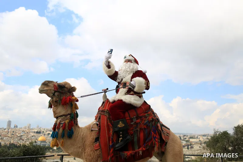 Palestinian Issa Kassissieh, dressed as Santa Claus, poses for a picture as he rides a camel at the Mount of Olives in Jerusalem, a few weeks before the upcoming holiday of Christmas on December 6, 2022. In Jerusalem's O...