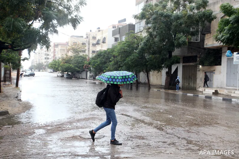 Palestinians walk in a street flooded by rain water, in Gaza city, on November 8, 2022. A cold front is expected to affect Palestine on Tuesday in the early morning hours, leading to a drop in temperature, becoming lower...