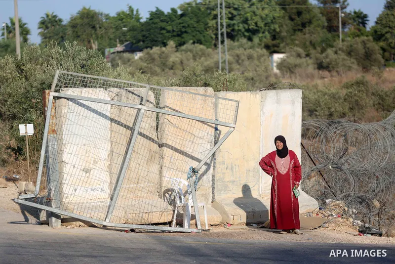 Palestinian farmers wait to enter to their lands that lie behind the separation wall to pick olives, in the town of Azzun, in the West Bank city of Qalqilya on October 19, 2022. The olive harvest is a national holiday an...