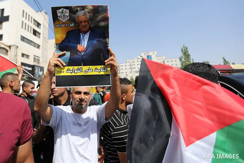 Palestinians wave national flags during the welcoming ceremony of President Mahmoud Abbas upon his return from Germany in the West Bank city of Ramallah on August 18, 2022. Photo by WAFA