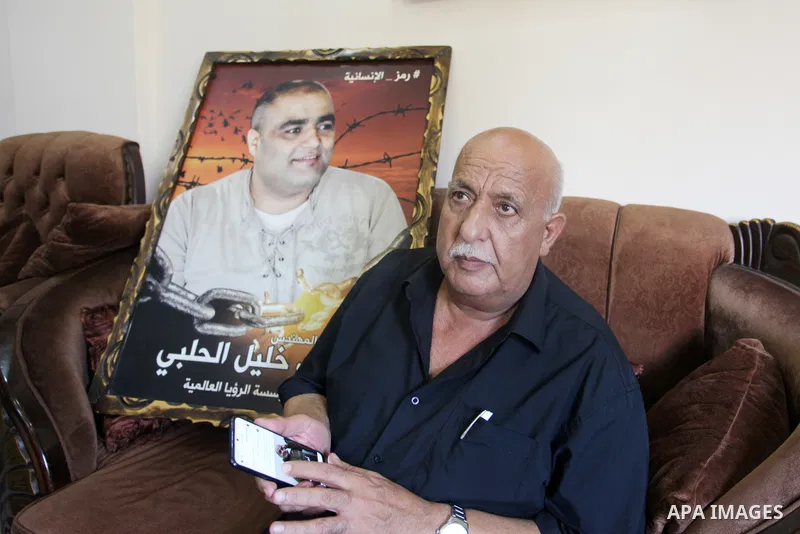 Family of World Vision's head Palestinian Mohammed al-Halabi, watch his picture on a phone after he was sentenced 12 years in prison by Israeli court, in Gaza city on August 30, 2022. An Israeli court on Tuesday sentence...