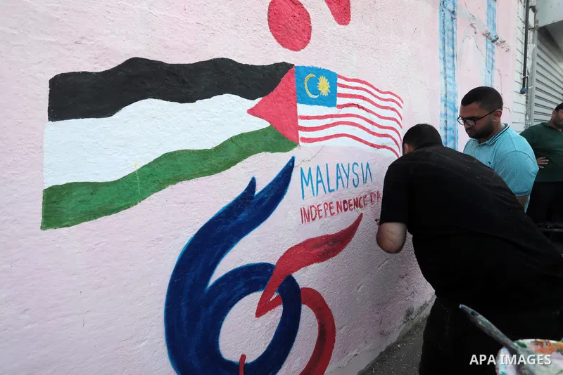 Palestinians attend the opening of a mural on the occasion of Malaysian National Day, in Gaza City on August 30, 2022. Malaysia's Independence Day is celebrated on August 31st. Also known as Merdeka Day (Freedom Day), th...