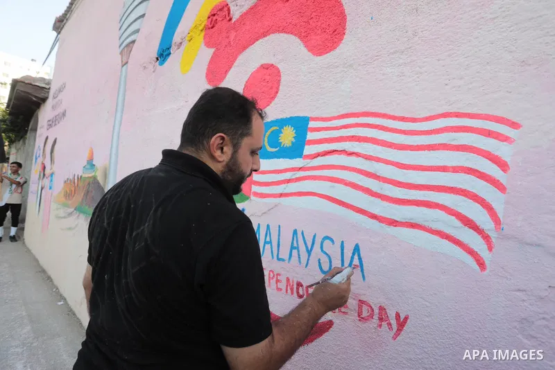 Palestinians attend the opening of a mural on the occasion of Malaysian National Day, in Gaza City on August 30, 2022. Malaysia's Independence Day is celebrated on August 31st. Also known as Merdeka Day (Freedom Day), th...