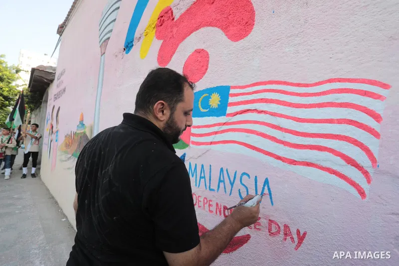 Palestinians attend the opening of a mural on the occasion of Malaysian National Day, in Gaza City on August 30, 2022. Malaysia's Independence Day is celebrated on August 31st. Also known as Merdeka Day (Freedom Day), th...