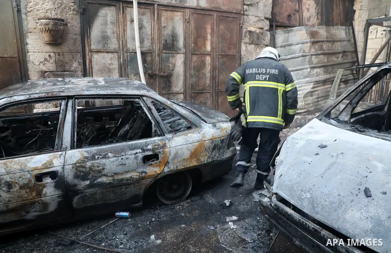 Palestinians inspect burnt-out cars during an Israeli military operation in the West Bank city of Nablus on July 24, 2022. Clashes between Israeli security forces and Palestinian have broken out in the city of Nablus in...