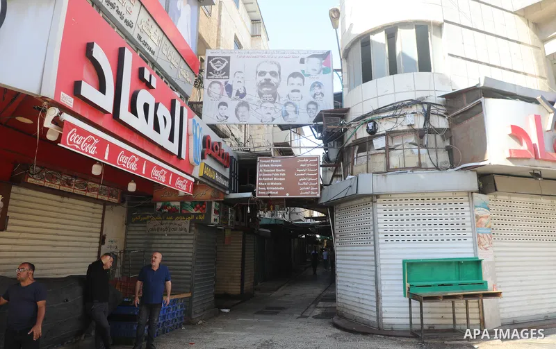 Palestinians walk near closed shops during a general strike, after Israeli forces killed Two Palestinians, in the West Bank city of Nablus on July 24, 2022. Two Palestinians were shot dead last night and ten others wound...