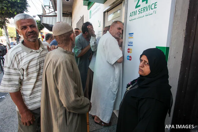 Palestinian of social affairs beneficiaries wait outside a bank to receive the payment of social affairs allowances for the first time in two years, in Gaza city, on July 6, 2022. Photo by Omar Ashtawy