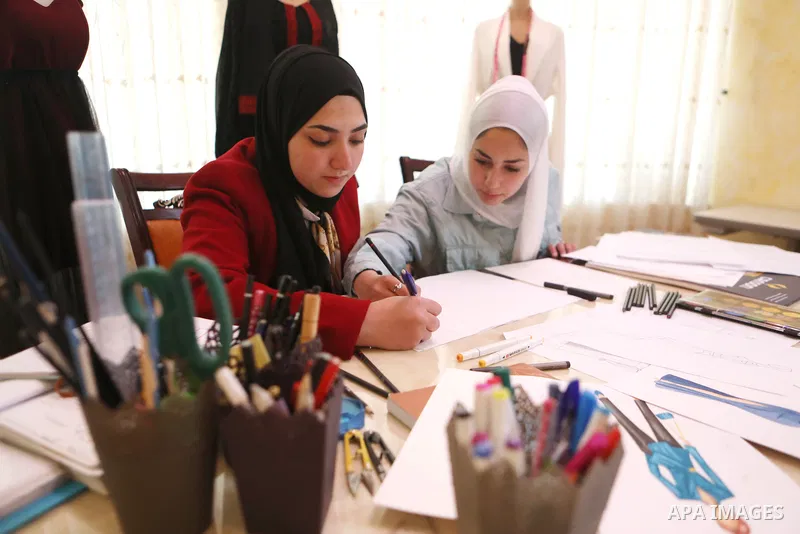Palestinian fashion designers Fatima Zalloum and Malak Jabari, work on fashion design at a home, in the West Bank city of Hebron on May 31, 2022. Two girls studied fashion design and opened a small business to draw and s...