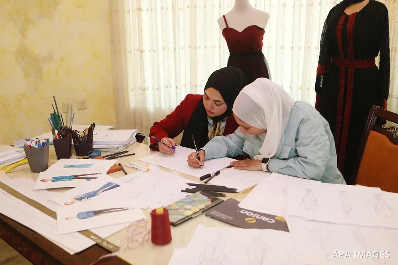Palestinian fashion designers Fatima Zalloum and Malak Jabari, work on fashion design at a home, in the West Bank city of Hebron on May 31, 2022. Two girls studied fashion design and opened a small business to draw and s...