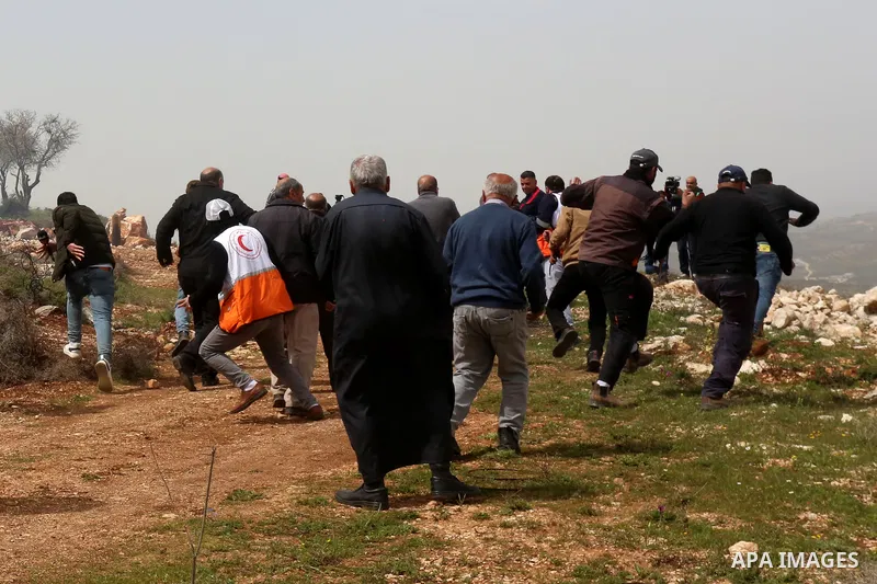 Palestinian farmers run for cover from tear gas canisters fired by Israeli security forces which preventing them plant olive trees on their land marking the Palestinian Land Day, at Qusra village near the West Bank City...
