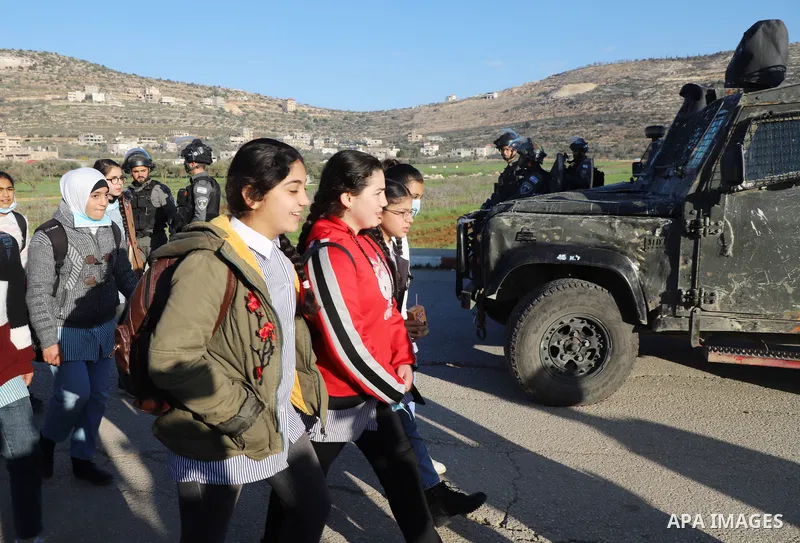 Palestinian students walk to their schools from the main road in al-Lubban al-Sharqiya village, south of Nablus city, in the West Bank on February 23, 2022. Dozens of rampaging Israeli settler fanatics today attacked the...