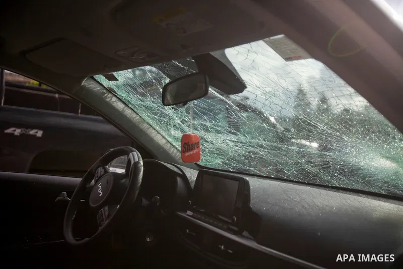 People gather around a car which was destroyed by Palestinian youth in the West Bank city of Nablus on March 18, 2023. According to local source, inside the car were Israeli settlers, while Israeli media said that the ca...