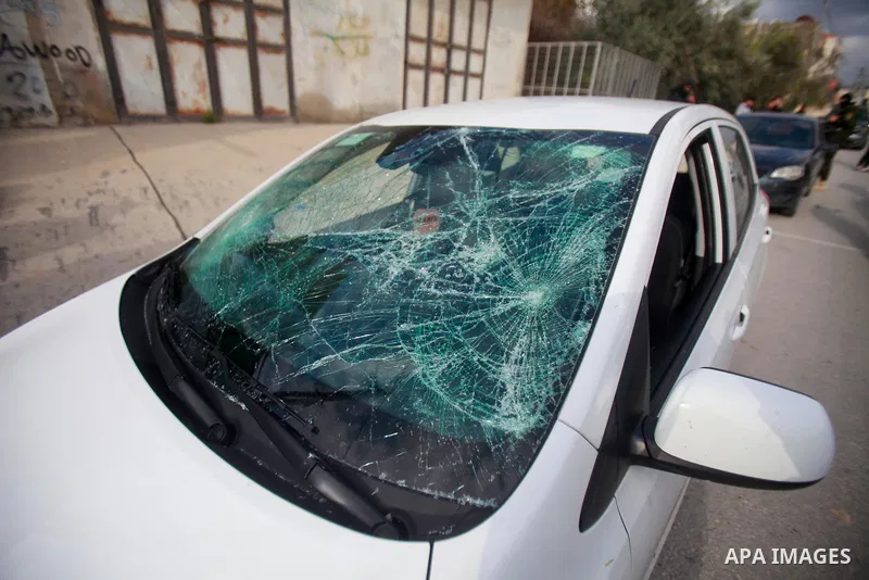 People gather around a car which was destroyed by Palestinian youth in the West Bank city of Nablus on March 18, 2023. According to local source, inside the car were Israeli settlers, while Israeli media said that the ca...