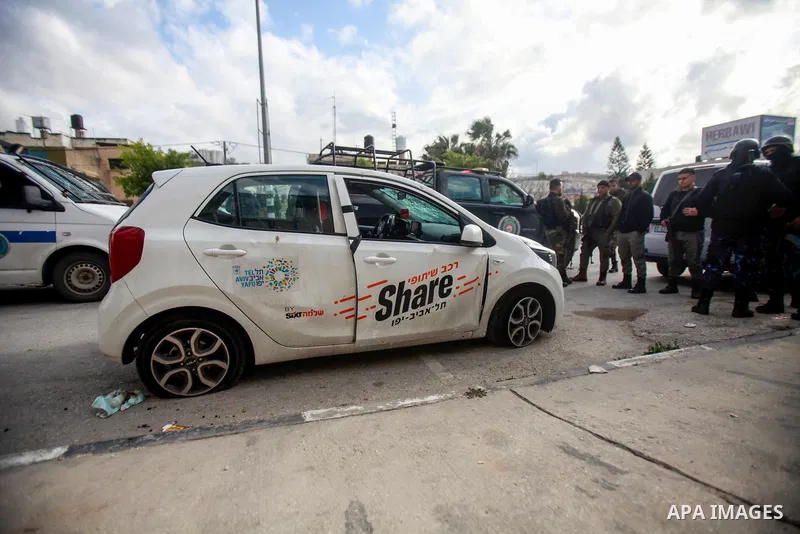 People gather around a car which was destroyed by Palestinian youth in the West Bank city of Nablus on March 18, 2023. According to local source, inside the car were Israeli settlers, while Israeli media said that the ca...