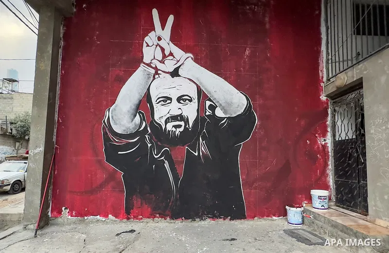 Palestinian artists work by a mural shows jailed Fatah leader Marwan Barghouti, in Jabalia refugee camp in the northern Gaza Strip on April 13, 2023. Marwan Barghouti, born in the West Bank village of Kobar in 1962, is a...