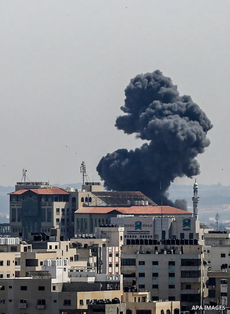 A plume of smoke rises above buildings in Gaza City during an israeli air strike on May 11, 2023. Israel and Gaza militants traded more heavy fire today, the third day of the worst escalation of violence in months that h...
