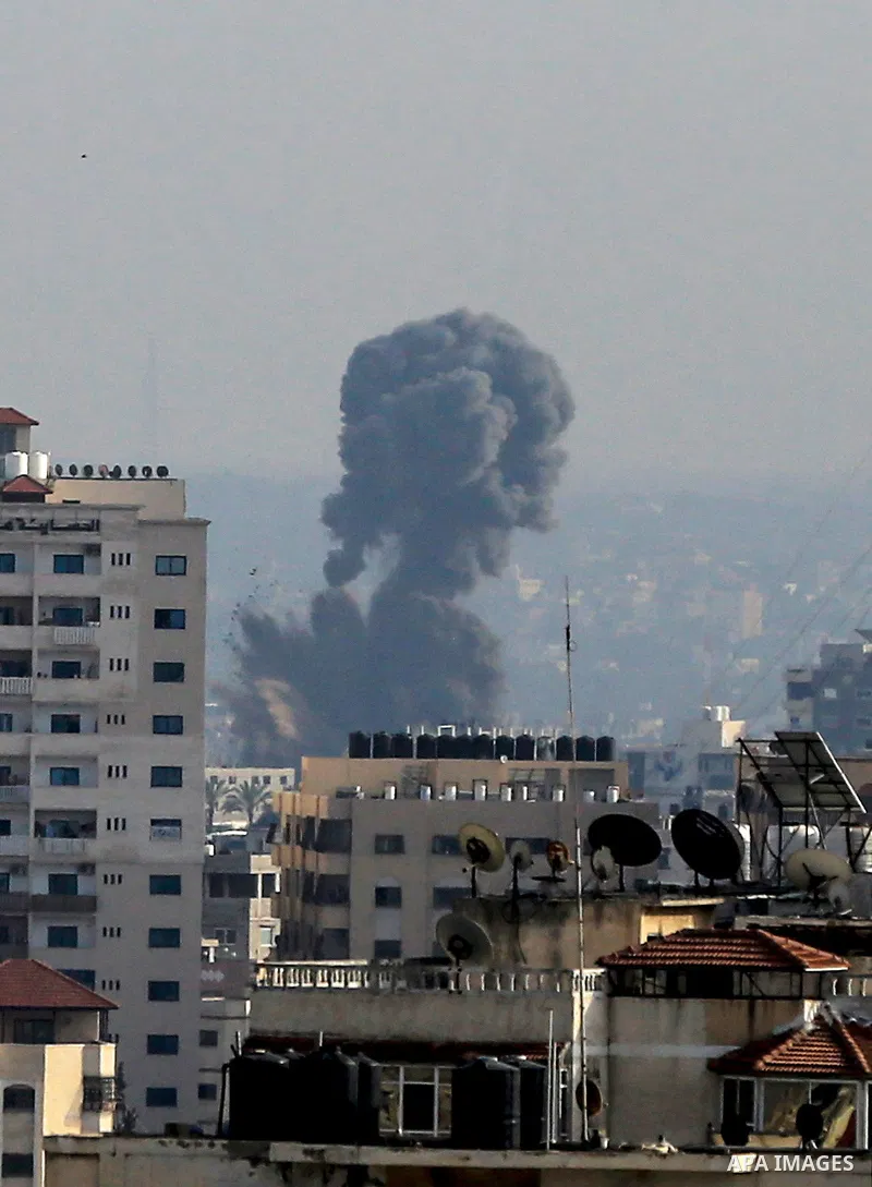A plume of smoke rises above buildings in Gaza City during an israeli air strike on May 11, 2023. Israel and Gaza militants traded more heavy fire today, the third day of the worst escalation of violence in months that h...