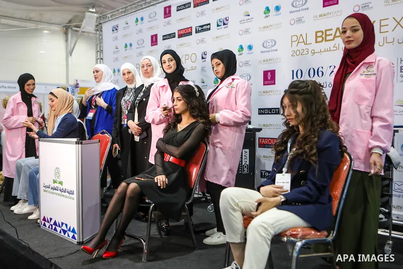 Palestinain female Beauticians make up women at beauty products fair, in the West Bank city of Hebron on June 11, 2023. Photo by Mamoun Wazwaz/APAimages
