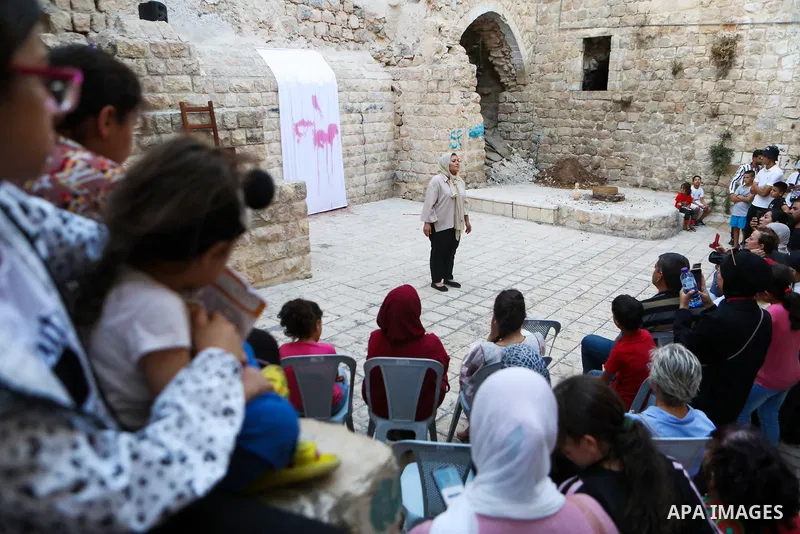 Palestinians attend a theatrical show "The Almond flower" in Aqabah neighbourhood in the Old City of Hebron, as part of the second edition of the Bethlehem site-specific Theater Festival on July 26, 2023. Photo by Mamoun...