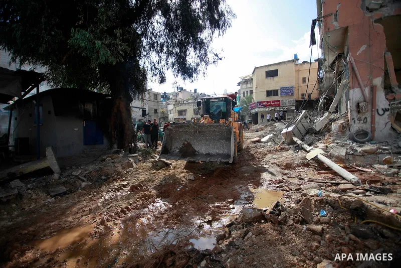 Palestinians walk next to a building damaged during a raid by Israeli troops at the Nur Shams refugee camp near the northern city of Tulkarm in the occupied West Bank on October 20, 2023. At least 81 Palestinians have be...