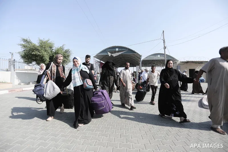 People walk through a gate to enter the Rafah border crossing to Egypt in the southern Gaza Strip on November 1, 2023. Scores of foreign passport holders trapped in Gaza started leaving the war-torn Palestinian territory...