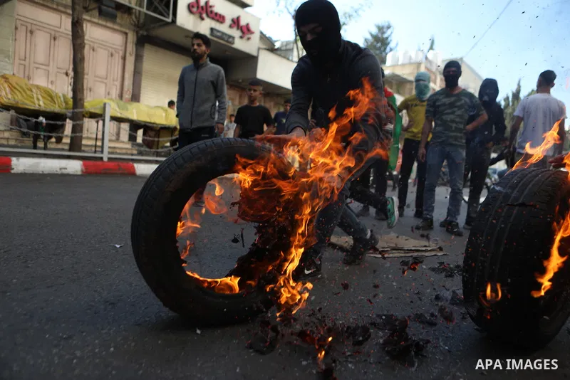 Palestinian youth roll burning tires during clashes with Israeli security forces following a protest supporting the Palestinian people following Friday Noon prayers in the West Bank city of Hebron on November 3, 2023, am...