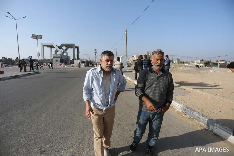 Palestinian workers, who were stranded in Israel since the October 7 attacks, walk near the Rafah border crossing with Egypt as they make their way to cross back into the Gaza Strip at the Kerem Shalom commercial border...