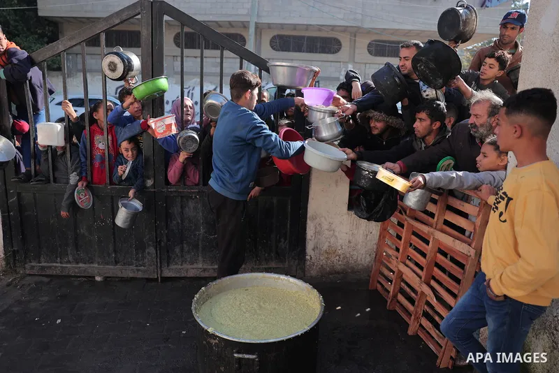 Palestinians gather with pots to receive food at a donation point provided by a charitable organization in Rafah in the southern Gaza Strip, on December 19, 2023. Photo by Bashar Taleb\ apaimages