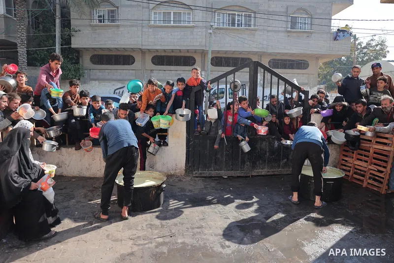 Palestinians gather with pots to receive food at a donation point provided by a charitable organization in Rafah in the southern Gaza Strip, on December 19, 2023. Photo by Bashar Taleb\ apaimages