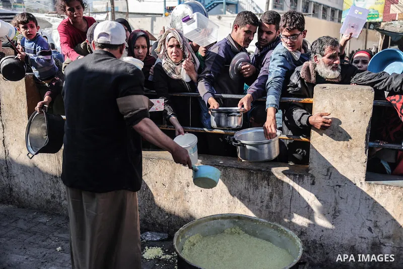 Palestinians gather with pots to receive food at a donation point provided by a charitable organization in Rafah in the southern Gaza Strip, on December 19, 2023. Photo by Bashar Taleb\ apaimages