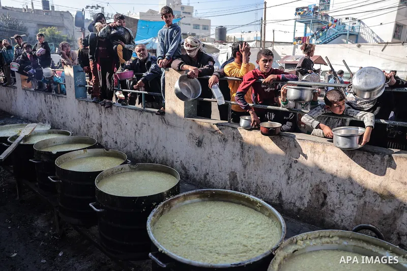 Palestinians gather with pots to receive food at a donation point provided by a charitable organization in Rafah in the southern Gaza Strip, on December 19, 2023. Photo by Bashar Taleb\ apaimages