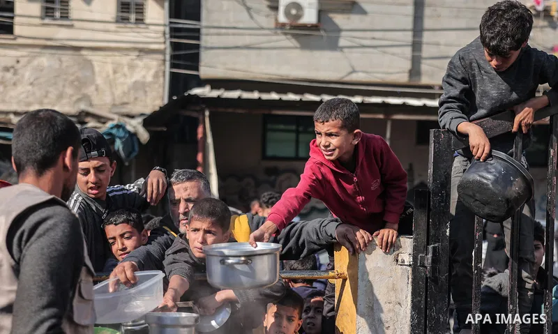 Palestinians gather with pots to receive food at a donation point provided by a charitable organization in Rafah in the southern Gaza Strip, on December 19, 2023. Photo by Bashar Taleb\ apaimages
