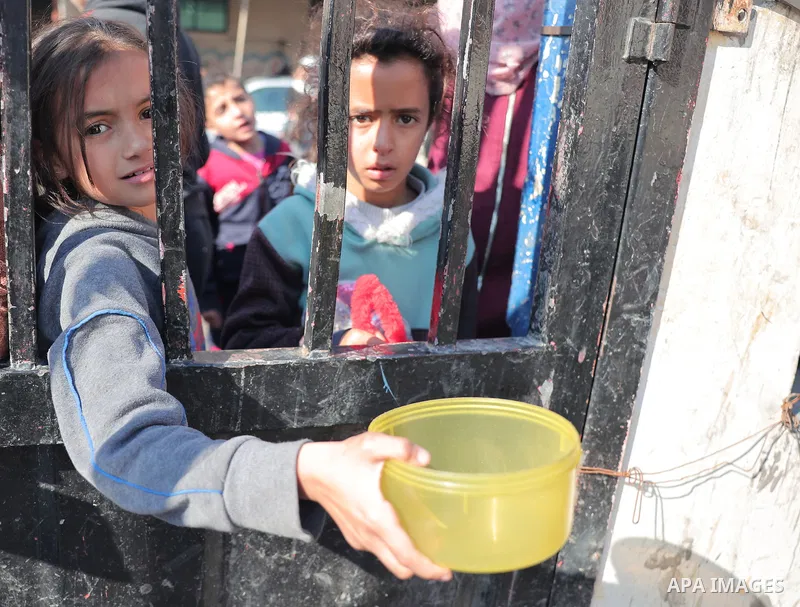 Palestinians gather with pots to receive food at a donation point provided by a charitable organization in Rafah in the southern Gaza Strip, on December 19, 2023. Photo by Bashar Taleb\ apaimages