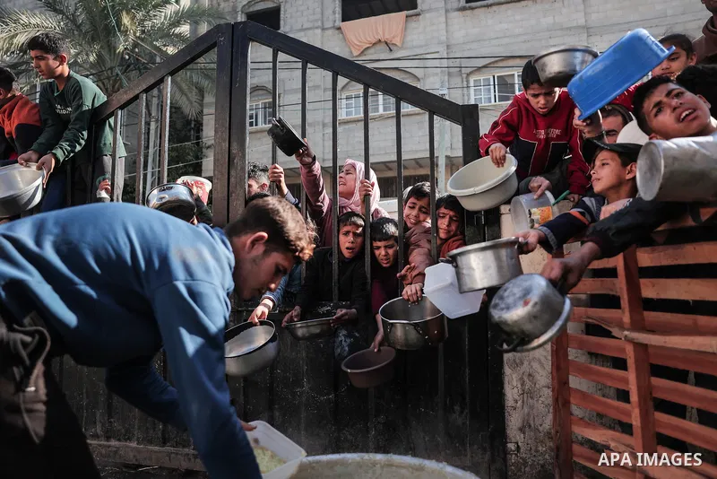 Palestinians gather with pots to receive food at a donation point provided by a charitable organization in Rafah in the southern Gaza Strip, on December 19, 2023. Photo by Bashar Taleb\ apaimages