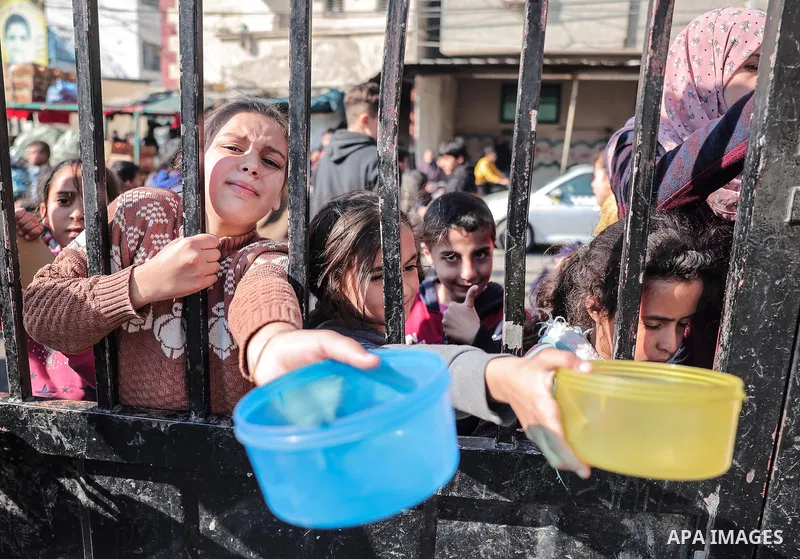 Palestinians gather with pots to receive food at a donation point provided by a charitable organization in Rafah in the southern Gaza Strip, on December 19, 2023. Photo by Bashar Taleb\ apaimages