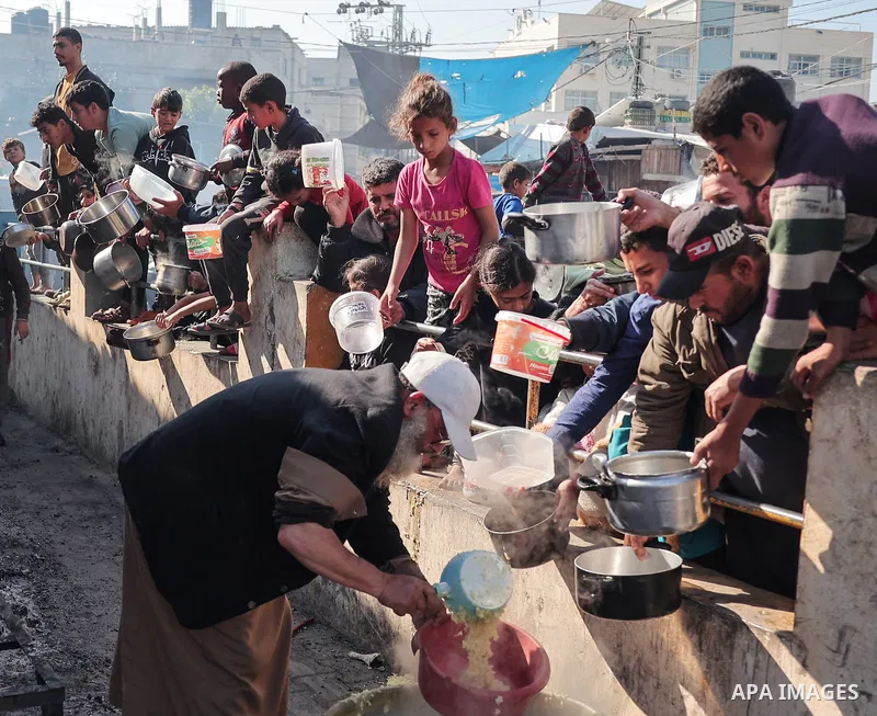 Palestinians gather with pots to receive food at a donation point provided by a charitable organization in Rafah in the southern Gaza Strip, on December 19, 2023. Photo by Bashar Taleb\ apaimages