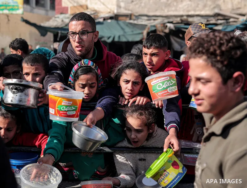 Palestinians gather with pots to receive food at a donation point provided by a charitable organization in Rafah in the southern Gaza Strip, on December 19, 2023. Photo by Bashar Taleb\ apaimages