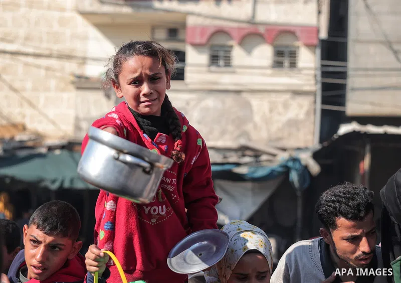Palestinians gather with pots to receive food at a donation point provided by a charitable organization in Rafah in the southern Gaza Strip, on December 19, 2023. Photo by Bashar Taleb\ apaimages