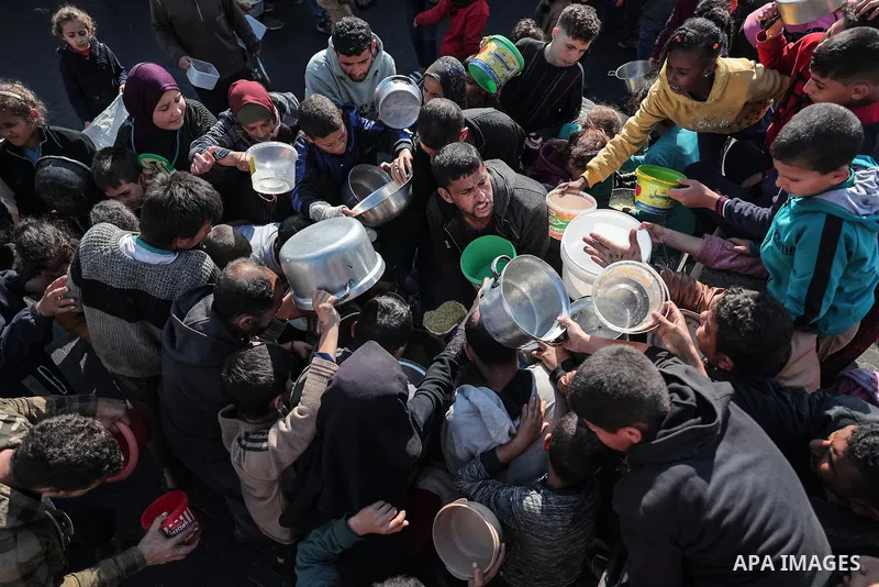 Palestinians gather with pots to receive food at a donation point provided by a charitable organization in Rafah in the southern Gaza Strip, on December 19, 2023. Photo by Bashar Taleb\ apaimages