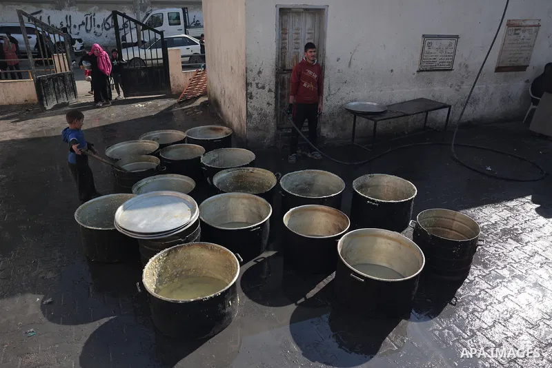 Palestinians gather with pots to receive food at a donation point provided by a charitable organization in Rafah in the southern Gaza Strip, on December 19, 2023. Photo by Bashar Taleb\ apaimages