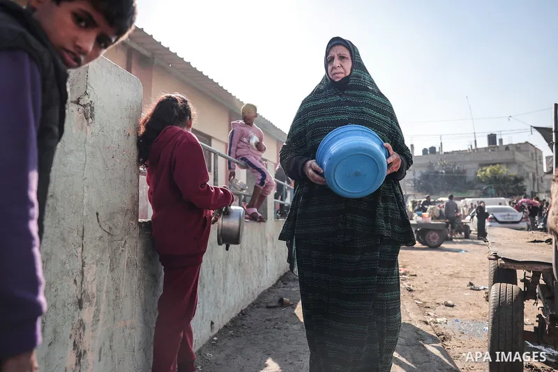 Palestinians gather with pots to receive food at a donation point provided by a charitable organization in Rafah in the southern Gaza Strip, on December 19, 2023. Photo by Bashar Taleb\ apaimages