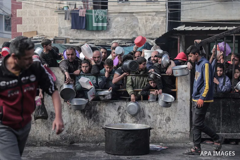 Palestinians wait to collect food at a donation point in a refugee camp in Rafah in the southern Gaza Strip on December 24, 2023. Photo by Bashar Taleb\ apaimages