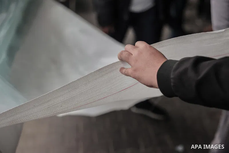 Palestinians buy large pieces of plastic sheeting from the Rafah market, on December 25, 2023. people use plastic sheeting to set up traditional tents in camps set up to shelter the palestinian displaced in Rafah, south...