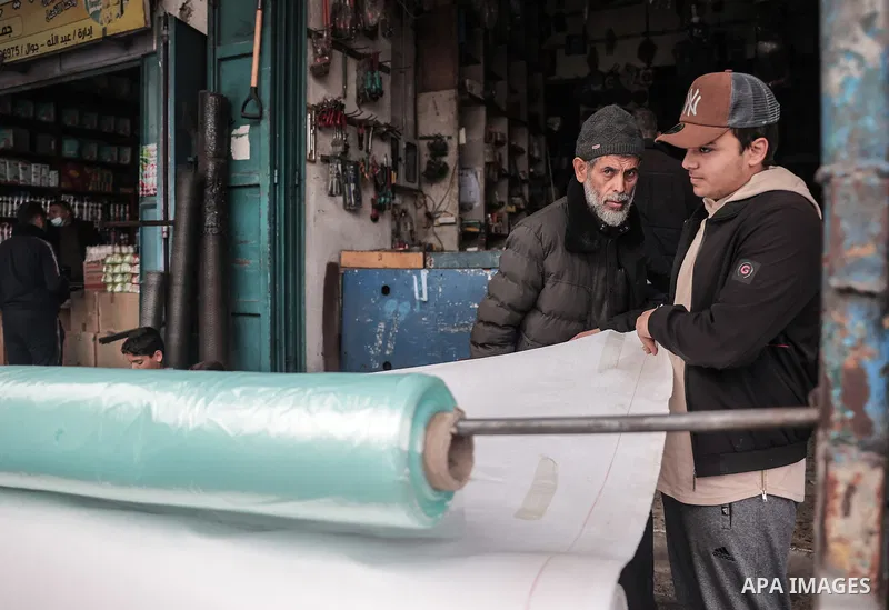 Palestinians buy large pieces of plastic sheeting from the Rafah market, on December 25, 2023. people use plastic sheeting to set up traditional tents in camps set up to shelter the palestinian displaced in Rafah, south...